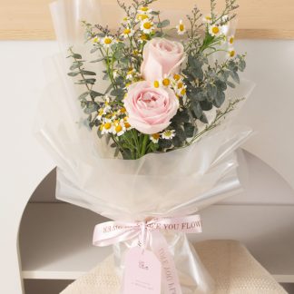 ช่อดอกกุหลาบสีชมพู 2 ดอก ช่อเล็ก แซมดอกเดซี่และยูคาลิปตัสใบกลม ห่อกระดาษใส ขึ้นเงา ดูไร้เดียงสา